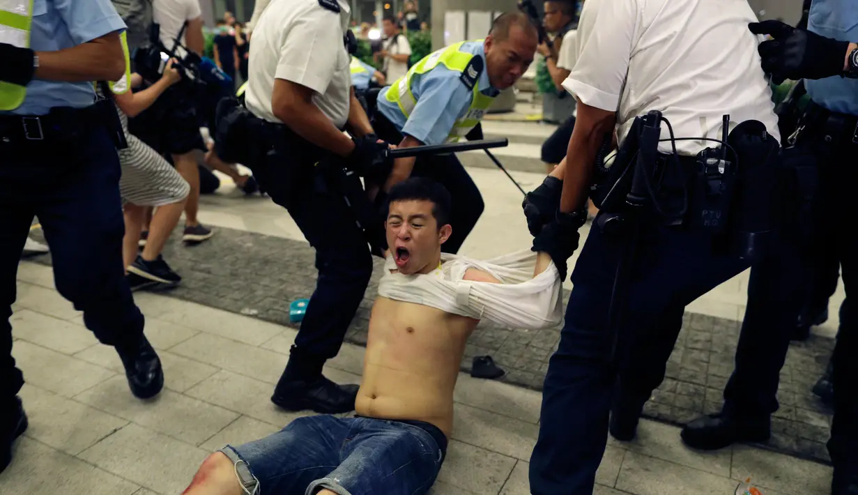 Polisi menyeret pengunjuk rasa yang menolak RUU Ekstradisi di luar gedung parlemen, Hong Kong, Senin (10/6/2019). Unjuk rasa ini disinyalir sebagai salah satu protes terbesar di Hong Kong sejak 2003 lalu terkait hukum keamanan nasional. (AP Photo/Vincent Yu)