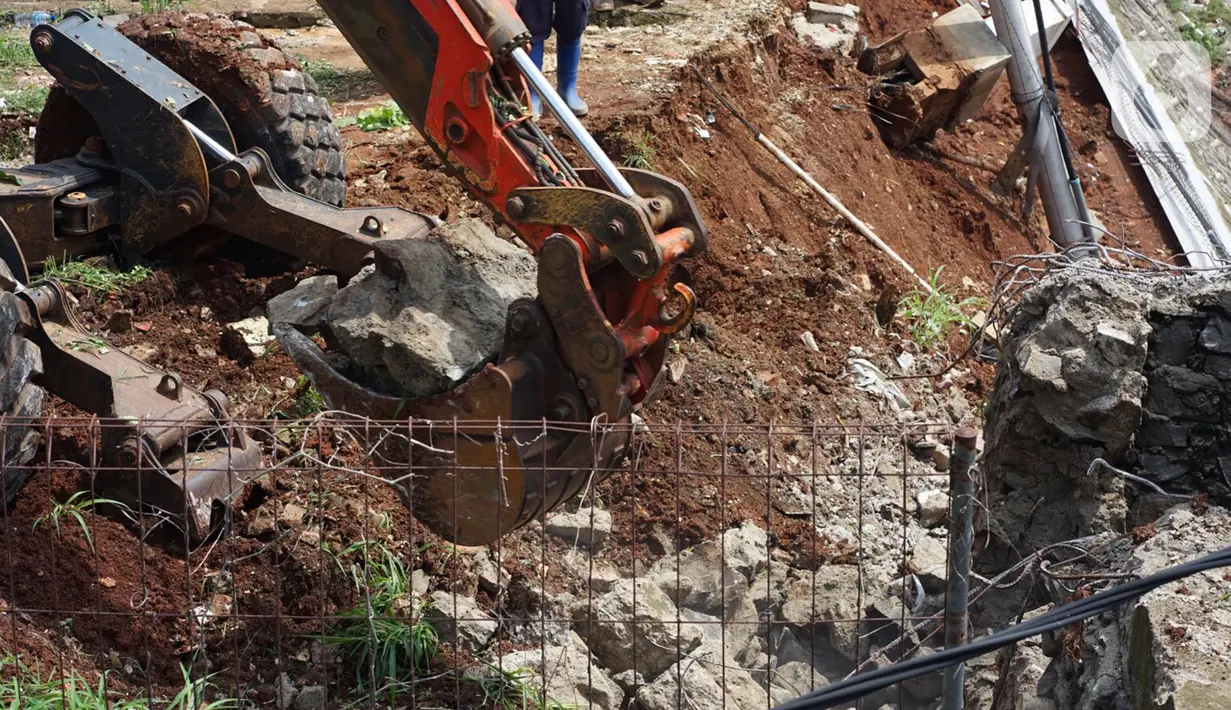 Petugas menggunakan alat berat berusaha merapikan posisi turap yang hancur di Jalan Damai, Ciganjur, Jakarta Selatan, Minggu (11/10/2020). Banjir sekaligus longsor tersebut mengakibatkan dua orang luka-luka dan satu orang meninggal dunia. (Liputan6.com/Immanuel Antonius)