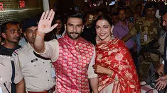 Pasangan pengantin baru, Ranveer Singh dan Deepika Padukone menyapa penggemar yang menyambut mereka di bandara internasional Mumbai, Minggu (18/11). Pasangan bintang Bollywood India itu baru saja kembali dari acara pernikahan mereka di Italia. (AFP)