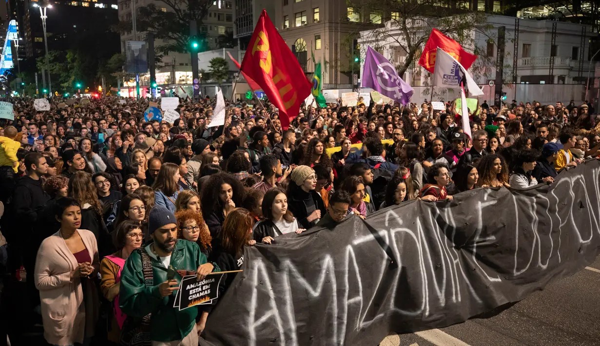 Demonstran berbaris memegang spanduk bertulis bahasa Portugis 'Amazon adalah milik rakyat' selama protes menuntut tindakan dari pemerintah Brasil memerangi kebakaran hutan Amazon di Sao Paulo, Brasil, Jumat (23/8/2019). (AP Photo/Andre Penner)