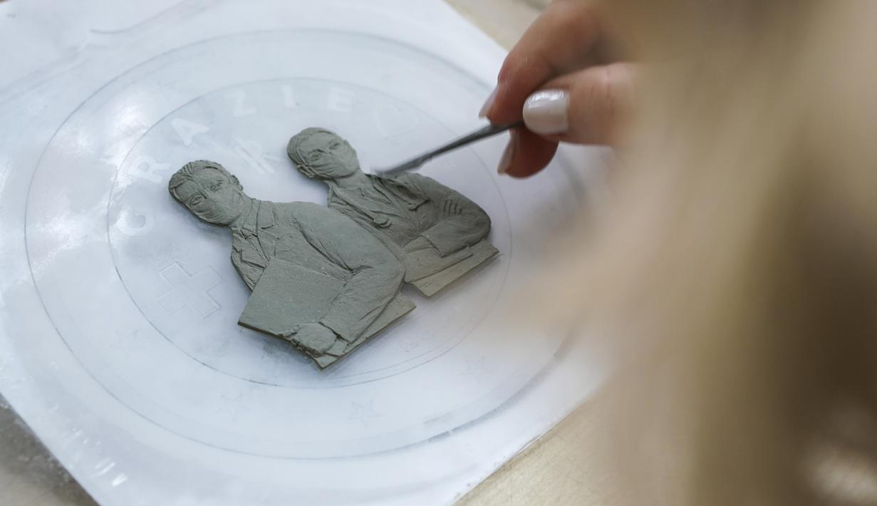 Seniman menyelesaikan koin 2 Euro yang didedikasikan untuk garda terdepan penanganan virus corona di percetakan uang negara Italia, di Roma, Kamis (21/1/2021). Koin peringatan tersebut dibuat dalam tiga seri yang dicetak dalam tiga juta eksemplar dan akan diedarkan secara umum. (AP/Andrew Medichini)