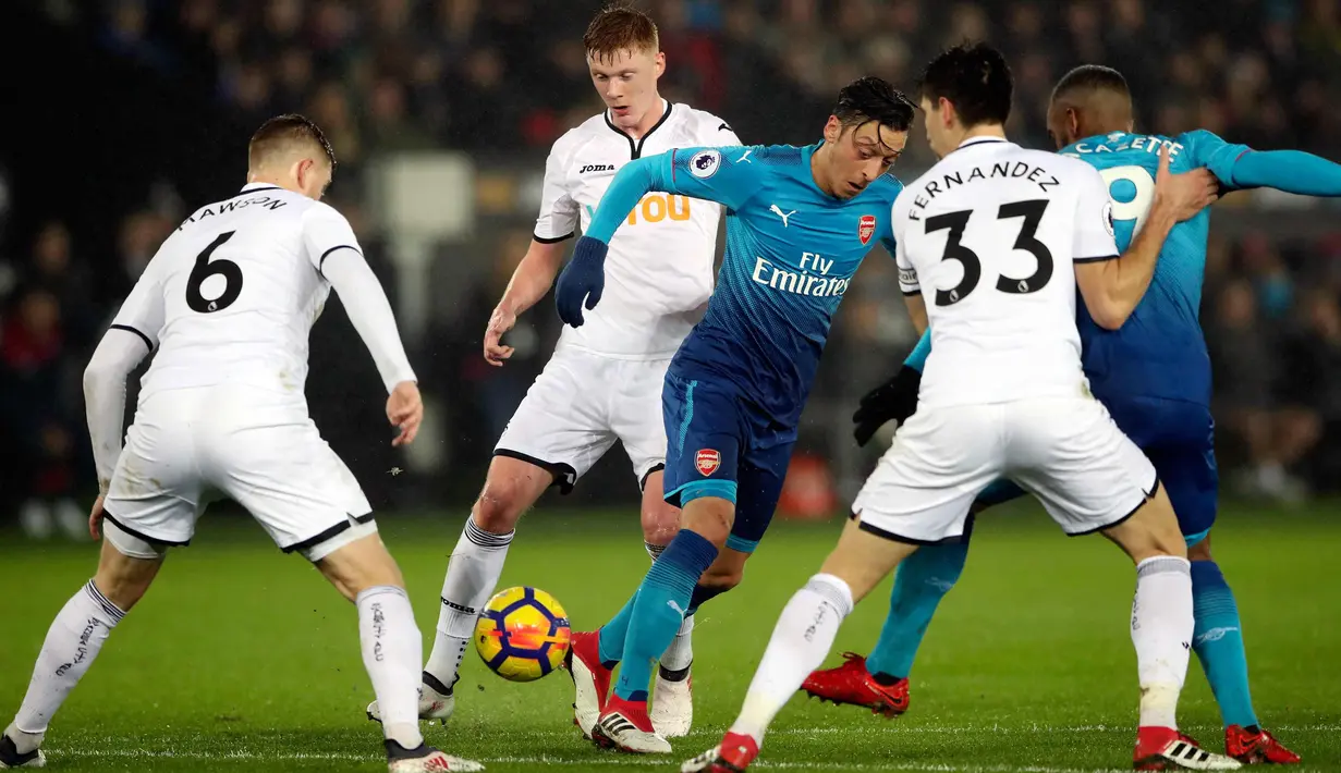 Tiga pemain Swansea City berusaha merebut bola yang dibawa pemain Arsenal Mezut Ozil pada lanjutan Liga Inggris di Stadion Liberty, Swansea, Wales, (30/1). Swansea City menang 3-1 atas Arsenal. (Nick Potts/PA via AP)