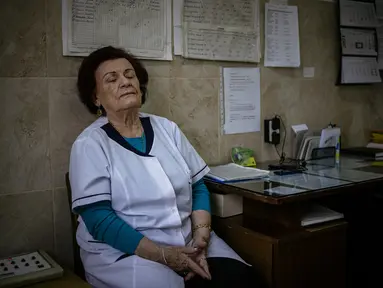 Gambar yang diambil pada 20 Januari 2021 ini menunjukkan spesialis penyakit menular Dr Maria Bogoeva (82) beristirahat sejenak saat bertugas di unit Covid-19 di sebuah rumah sakit kecil di Bulgaria. Maria Bogoeva siap untuk pensiun ketika pandemi virus corona melanda. (Dimitar DILKOFF/AFP)
