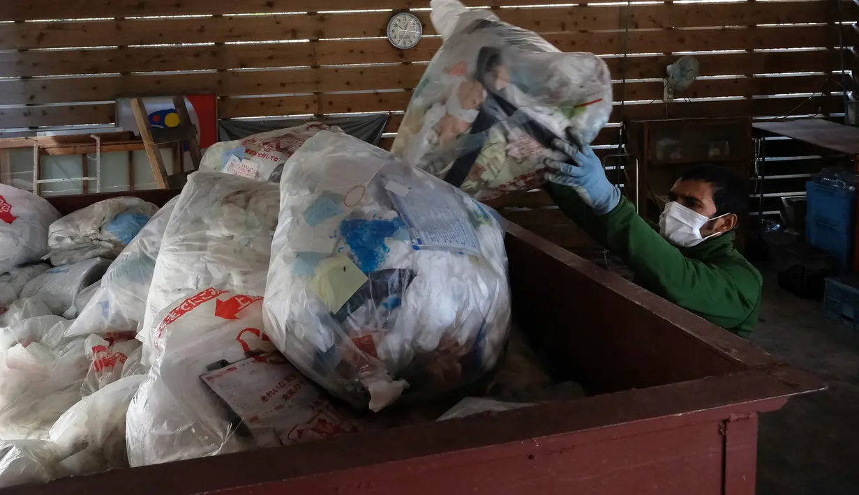Pekerja mengumpulkan sampah yang telah dipisahkan di pusat limbah di Kamikatsu, Prefektur Tokushima, 14 Maret 2019. Kota di barat daya Jepang ini mengumumkan pada tahun 2003 bahwa pada tahun 2020 akan berhenti menghasilkan limbah sama sekali sebagai tujuan zero waste-nya. (Kazuhiro NOGI/AFP)