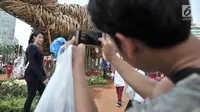 Pengunjung Car Free Day berfoto dengan latar belakang instalasi bambu "Getih Getah" di Bundaran HI, Jakarta, Minggu (19/8). Karya seni Joko Avianto itu langsung diserbu dan menjadi objek foto baru bagi sejumlah masyarakat. (Merdeka.com/ Iqbal S. Nugroho)