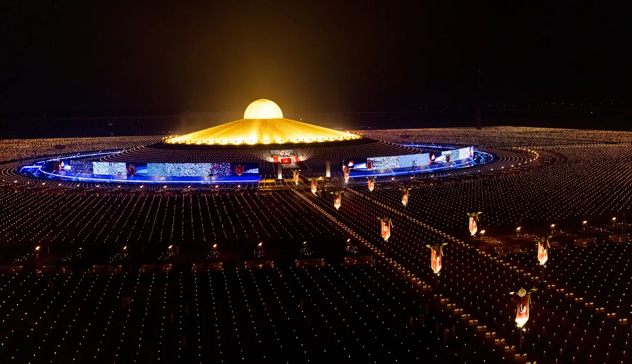 Kuil Wat Dhammakaya dikelilingi oleh lilin yang menyala selama perayaan Makha Bucha di provinsi Pathum Thani, utara Bangkok (16/2/2022). Hari raya ini dirayakan pada saat bulan purnama di tiap bulan ketiga kalender Buddha. (AFP/Jack Taylor)