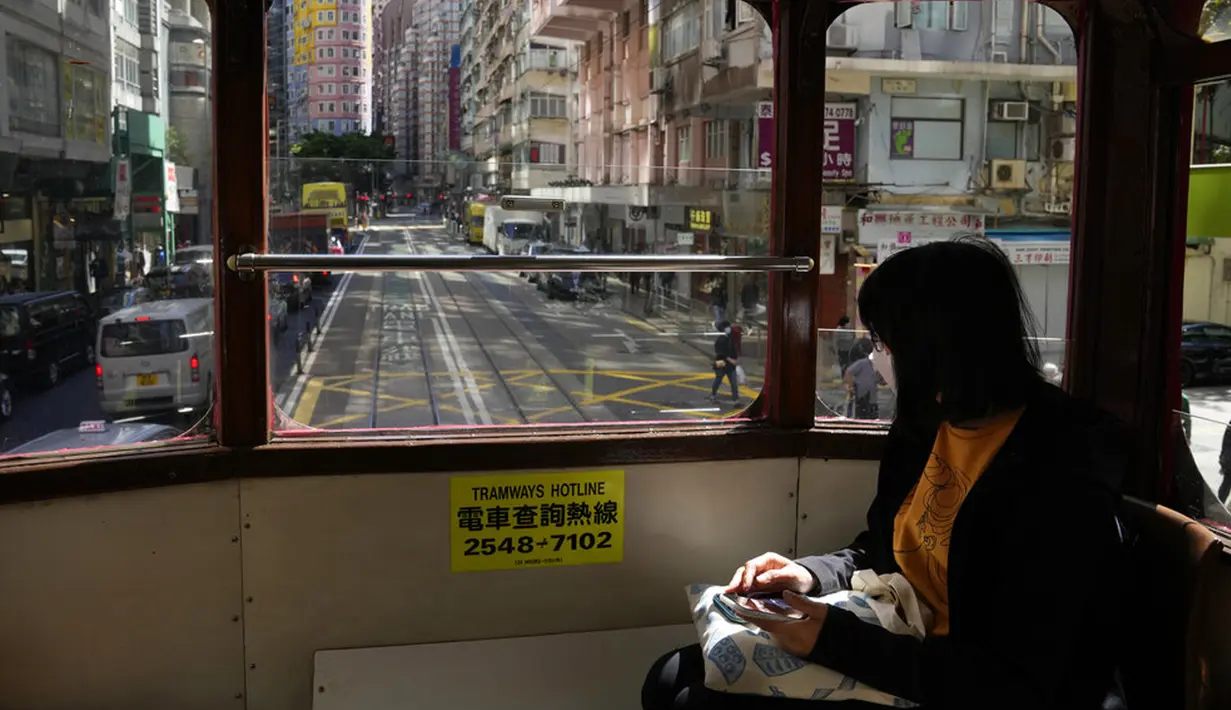 Seorang wanita mengenakan masker saat naik trem di Hong Kong, 8 Maret 2022. COVID-19 varian Omicron yang menyebar cepat membanjiri Hong Kong membuat kamar jenazah penuh, memaksa pihak berwenang untuk menyimpan jenazah dalam kontainer pengiriman berpendingin. (AP Photo/Kin Cheung)