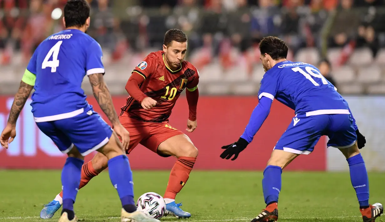 Kapten Timnas Belgia, Eden Hazard berebut bola dengan pemain Timnas Siprus, Christoforou Kypros pada laga Grup I Kualifikasi Piala Eropa 2020 di Cardiff City Stadium, Selasa (19/11/2019). Timnas Belgia memetik kemenangan telak dengan skor 6-1 kala menjamu Siprus. (JOHN THYS / AFP)