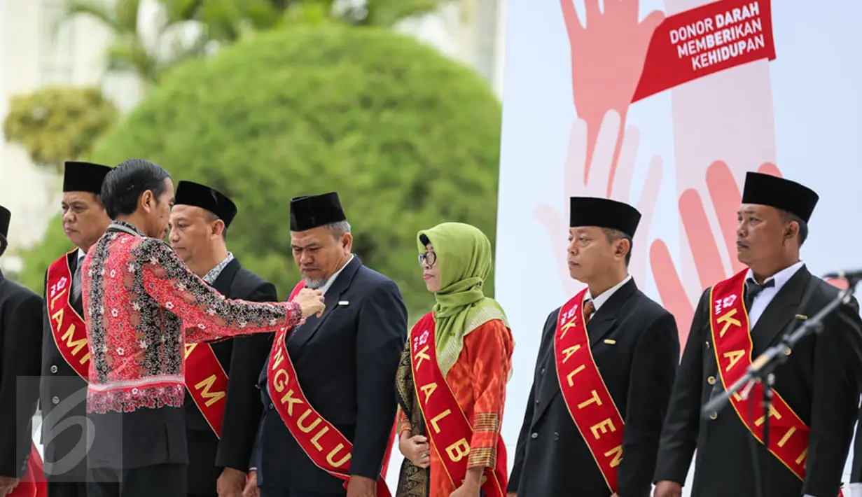 Presiden Joko Widodo (Jokowi) ketika memberikan Tanda Kehormatan Satyalencana Kebaktian Sosial kepada 893 orang yang telah melakukan 100 kali donor darah di Istana Bogor, Jawa Barat, Jumat (18/12). (Liputan6.com/Faizal Fanani)