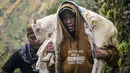 Seorang pria membawa seekor kambing sebagai persembahan saat berjalan mendaki Bukit Widodaren menjelang upacara Yadnya Kasada di kaki Gunung Bromo, Jawa Timur, pada Minggu 31 Mei 2026. (JUNI KRISWANTO/AFP)