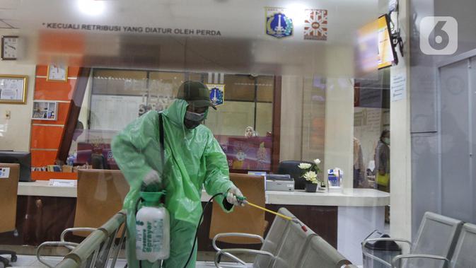 Petugas Satpol PP mengenakan jas hujan saat melakukan penyemprotan cairan disinfektan di Kantor Kecamatan Taman Sari, Jakarta, Selasa (17/3/2020). Penyemprotan dilakukan untuk mengantisipasi penyebaran virus corona COVID-19 di berbagai fasilitas publik. (Liputan6.com/Johan Tallo)