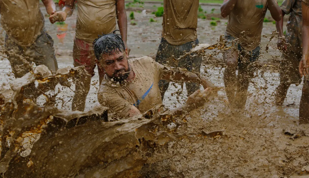 Sejumlah warga Nepal bermain di lumpur pada Asar Pandra, atau hari menanam padi nasional di Lalitpur, 29 Juni 2018. Asar Pandra diadakan sebagai tanda dimulainya kembali aktivitas tanam padi di sawah saat musim hujan tiba. (AP Photo/Niranjan Shrestha)