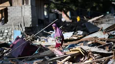 Seorang wanita mencari barang-barang yang tersisa di antara puing rumah akibat gempa dan tsunami di Donggala, Sulawesi Tengah, Jumat (5/10). Gempa bumi berkekuatan 7,4 skala richter melanda Palu dan Donggala pada 28 September 2018 lalu. (AFP/Jewel SAMAD)