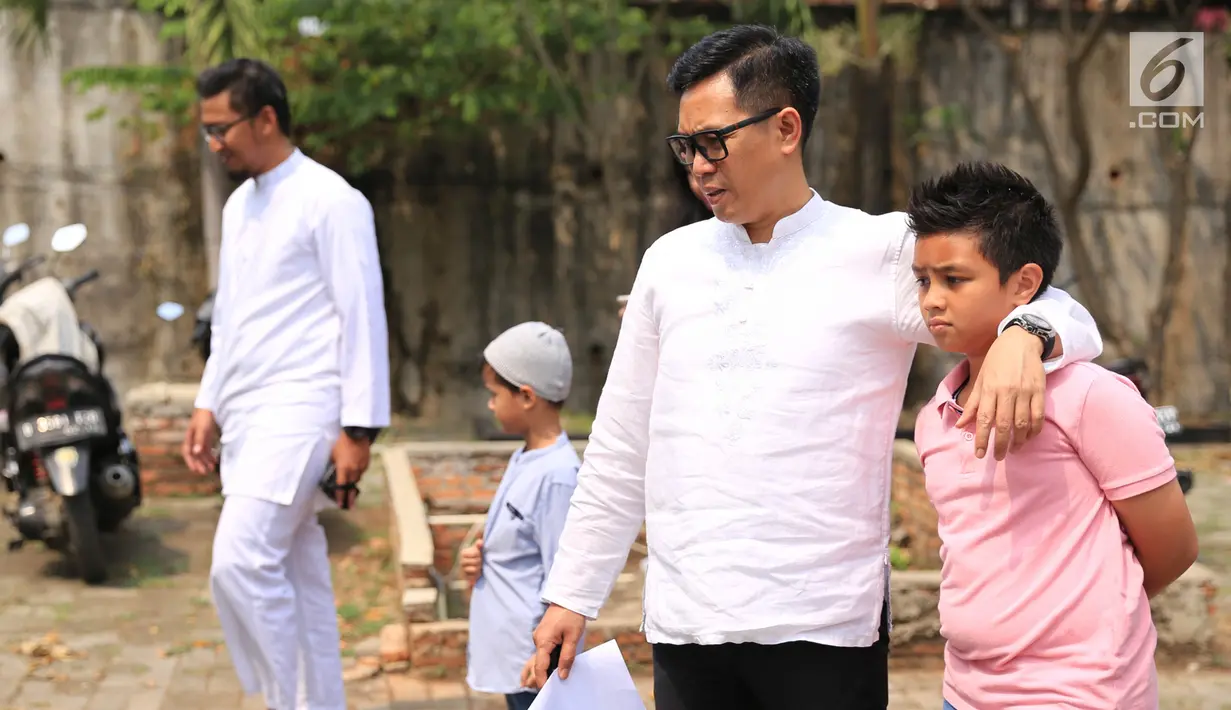 Presenter Eko Patrio ditemanin putranya melihat proses pemotongan hewan kurban di kawasan Cipinang, Jakarta, Jumat (1/9). Khusus di kantornya, Eko berkurban dua ekor sapi dan tiga ekor kambing. (Liputan6.com/Herman Zakharia)