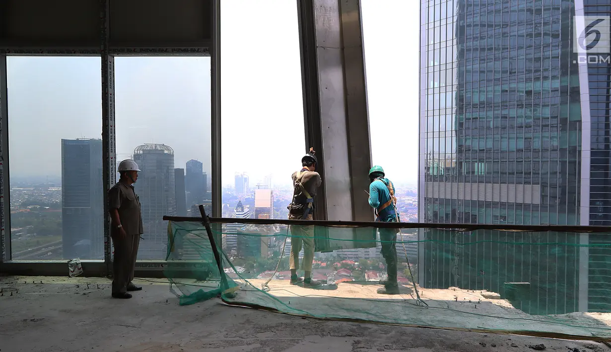 Pekerja Nusa Konstruksi Enjiniring memasang kaca gedung World Capital Tower, di Mega Kuningan, Jakarta, Rabu (13/9). Salah satu gedung tertingi di Jakarta ini akan menambah pasokan ruang perkantoran, ritel dan hiburan. (Liputan6.com/Fery Pradolo)
