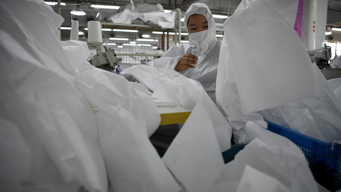Pekerja menjahit bahan untuk digunakan membuat pakaian antivirus di pabrik garmen Zhejiang Ugly Duck Industry, di Wenzhou, 28 Februari 2020. Wabah virus corona di China membuat produsen pakaian itu mulai memproduksi baju hazmat yang banyak diburu orang untuk melindungi dirinya. (NOEL CELIS/AFP)