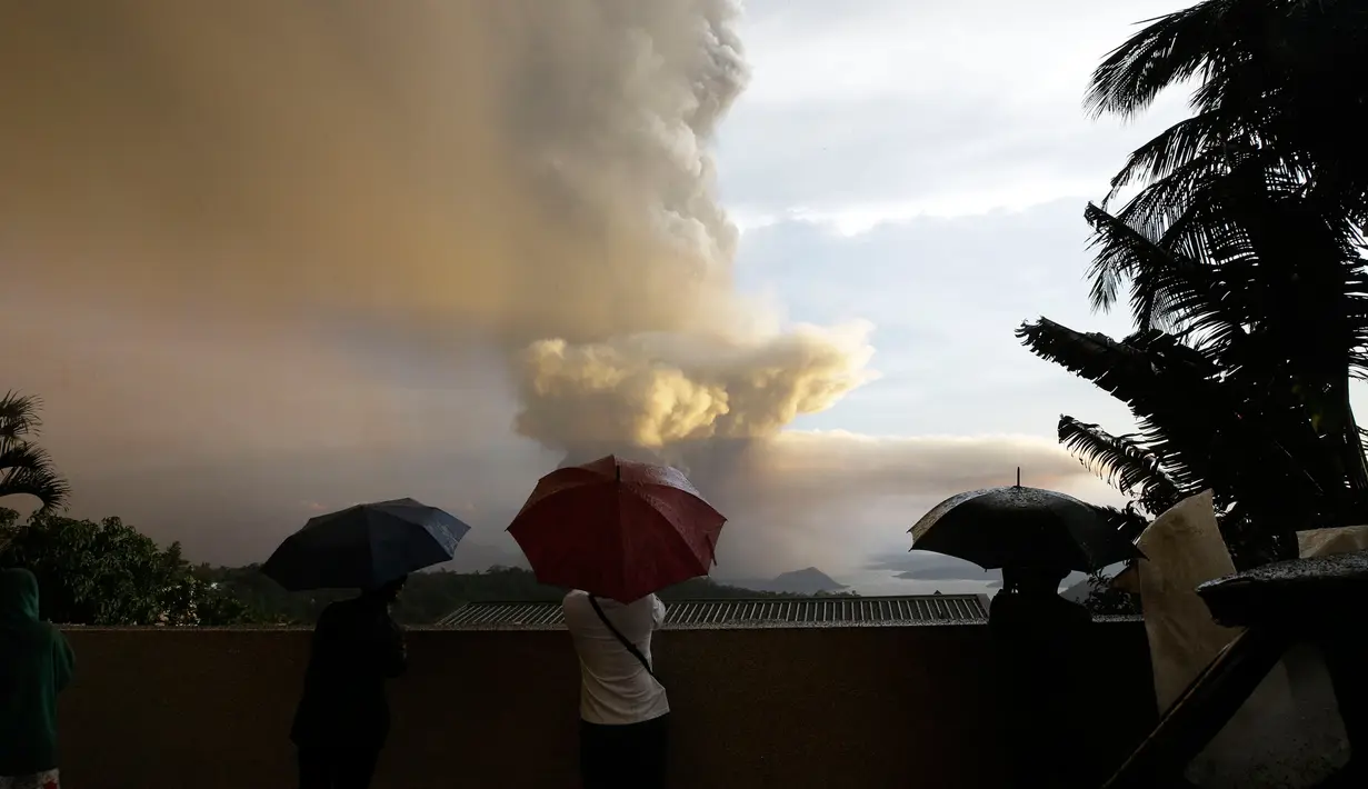 Sejumlah orang menyaksikan Gunung Api Taal erupsi di Tagaytay, Provinsi Cavite, Filipina, Minggu (12/1/2020). Gunung Api Taal mengeluarkan awan abu mencapai 50.000 kaki (15.000 meter) ke atmosfer. (AP Photo/Aaron Favila)