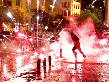 Demonstran antipemerintah melemparkan petasan ke arah polisi antihuru-hara saat demonstrasi menentang pemerintahan baru di dekat Parliament Square, Beirut, Lebanon, Rabu (22/1/2020). Demonstrasi dan kekerasan terus berlanjut kendati Lebanon telah mengumumkan kabinet baru. (AP Photo/Hussein Malla)