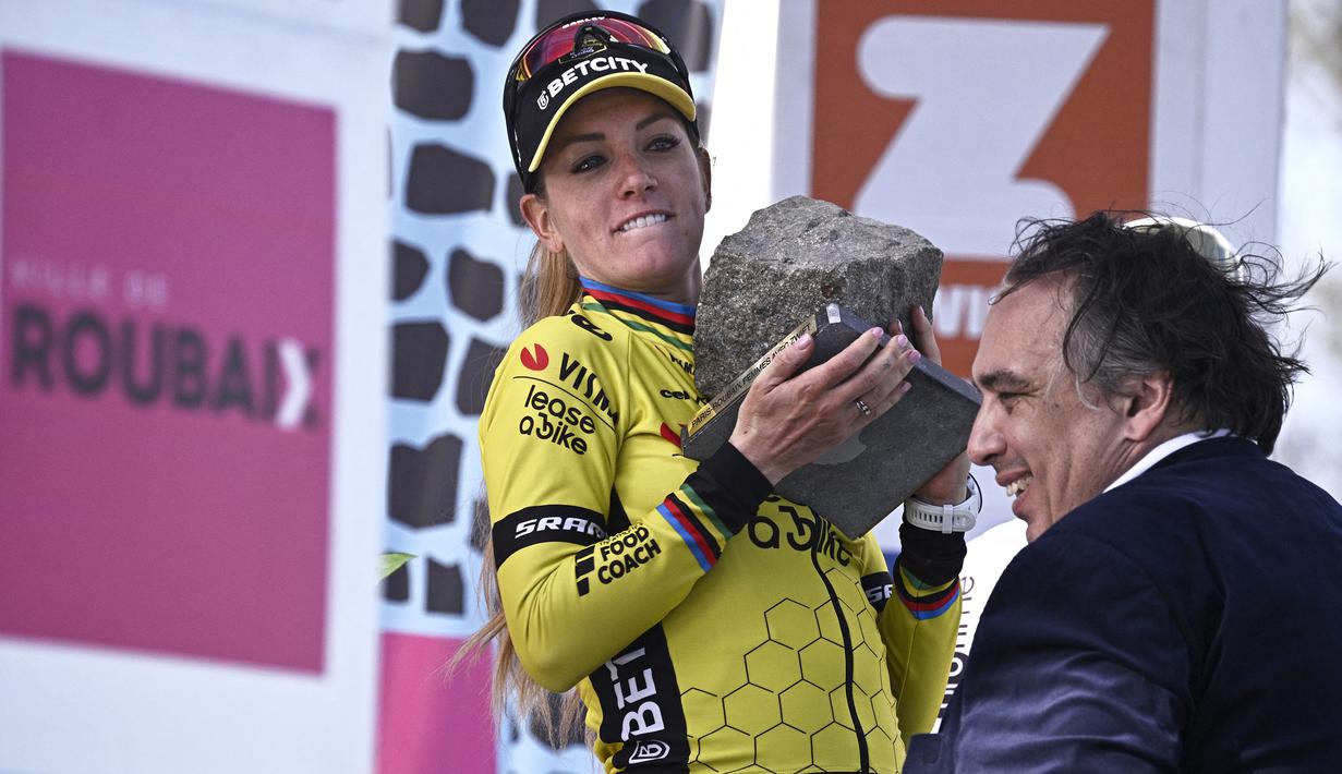 Ekspresi pembalap Team Visma-Lease, Pauline Ferrand-Prevot saat menjunjung trofi kemenangan Paris Roubaix Femmes 2025 pada Sabtu (12/04/2025) waktu setempat. Perlombaan tersebut menempuh 148,5 km dari Denain hingga Roubaix, Prancis. (AFP/Julien De Rosa)