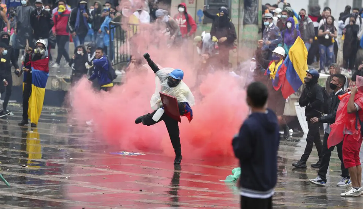 Seorang pengunjuk rasa antipemerintah mengembalikan tabung gas air mata ke polisi saat bentrokan di Bogota, Kolombia, Rabu (5/5//2021). Protes menentang proposal reformasi pajak terus berlanjut meski Presiden Ivan Duque telah mencabutnya. (AP Photo/Fernando Vergara)