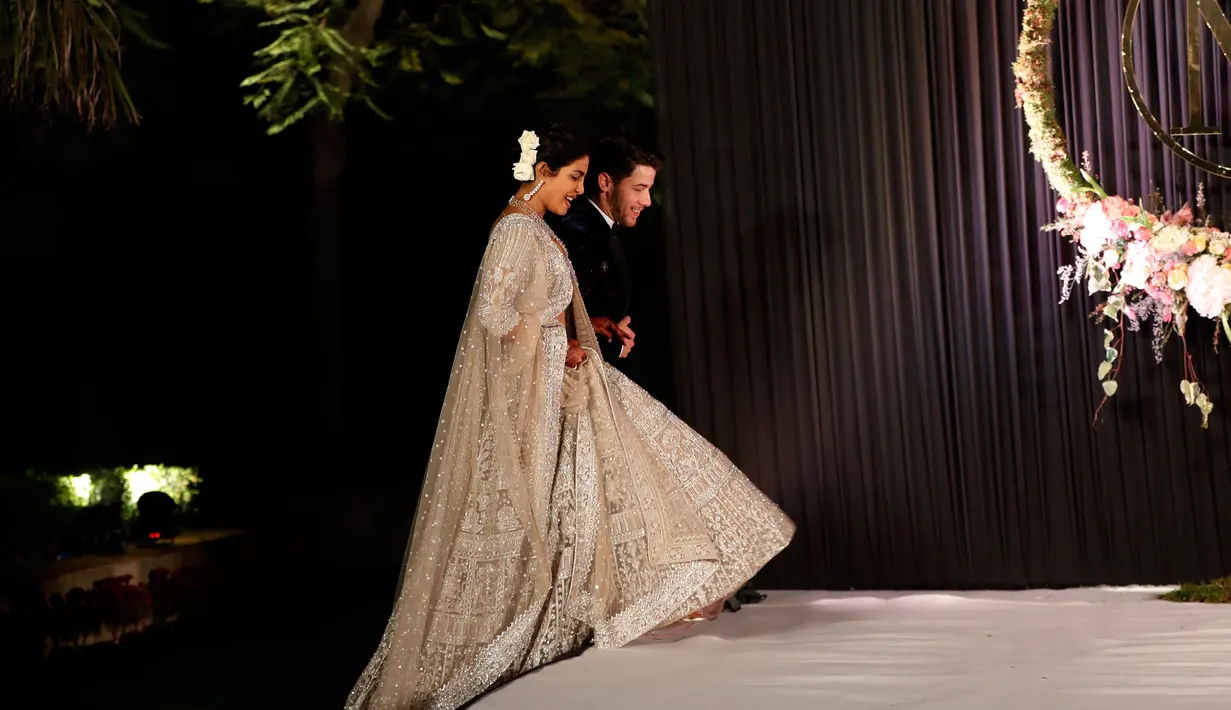 Aktris Bollywood Priyanka Chopra dan musisi AS Nick Jonas berjalan saat resepsi pernikahan mereka di New Delhi, India, Selasa (4/12). Priyanka Chopra dan Nick Jonas menikah dalam dua upacara yang berbeda. (AP Photo/Altaf Qadri)