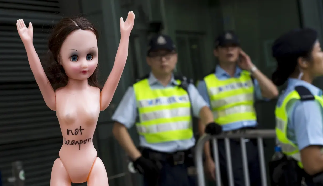 Pengunjuk rasa membawa boneka di luar markas polisi di kawasan Wan Chai, Hong Kong, Minggu (2/8). Demo tersebut merupakan aksi simpati terhadap seorang perempuan yang di penjara karena dituduh menyerang polisi menggunakan payudaranya. (REUTERS/Tyrone Siu)