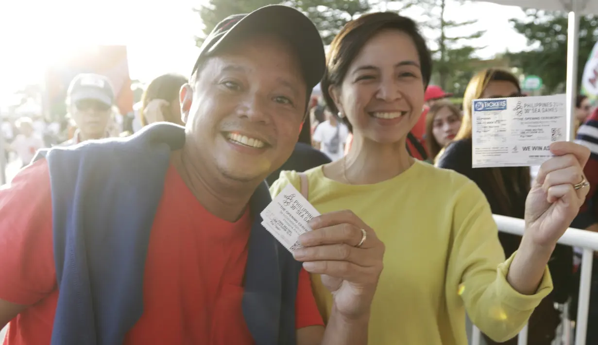 Sepasang penonton menunjukan tiket masuk jelang upacara pembukaan SEA Games 2019 di Philipine Arena Bulacan, Manila, Sabtu (30/11). Pesta olahraga se-Asia Tenggara ini akan berlangsung hingga 11 Desember. (Bola.com/M Iqbal Ichsan)