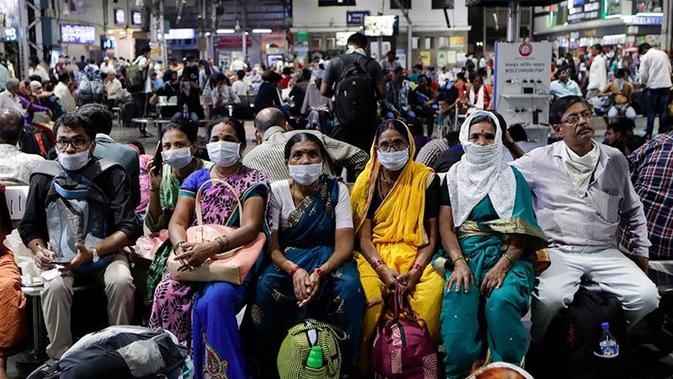 Orang India yang menunggu di stasiun kereta api memakai masker pelindung sebagai tindakan pencegahan terhadap pandemi Virus Corona. (Rajanish Kakade / AP Photo]