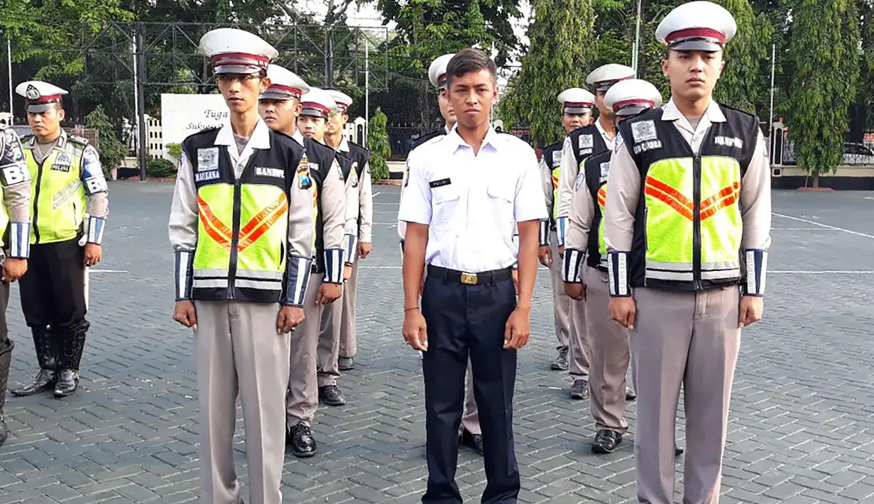 Pria bernama Polisi (Kemeja putih) berbaris dan anggota kepolisian di Polres Pasuruan (21/11). Sebelumnya, Polisi bekerja sebagai kuli bangunan. Akibat viral di medsos karena namanya yang unik, Polisi ditugaskan di Satlantas Polres Pasuruan. (AFP Photo)