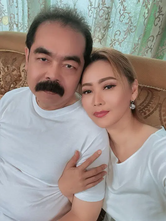 Dalam foto, Inul Daratista dan Adam Suseno kompak pakai atasan putih polos tanpa lengan. Bintang sinetron Kenapa Harus Inul? merengkuh lengan suami. “Lihatlah kita berdua. Coba lihat Mas Adam, dulu cakep sekali. Sekarang matanya juga sudah mulai turun, rambutnya sudah makin botak kalau dihitung tinggal 10 helai sendiri2 pula,” ujarnya. (Foto: Dok. Instagram @inul.d)