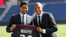 Penyerang PSG, Kylian Mbappe dan CEO Nasser Al-Khelaifi menunjukkan jersey klub PSG usai resmi bergabung dalam konferensi pers bersama PSG di Paris, (6/9). (AP Photo / Christophe Ena)