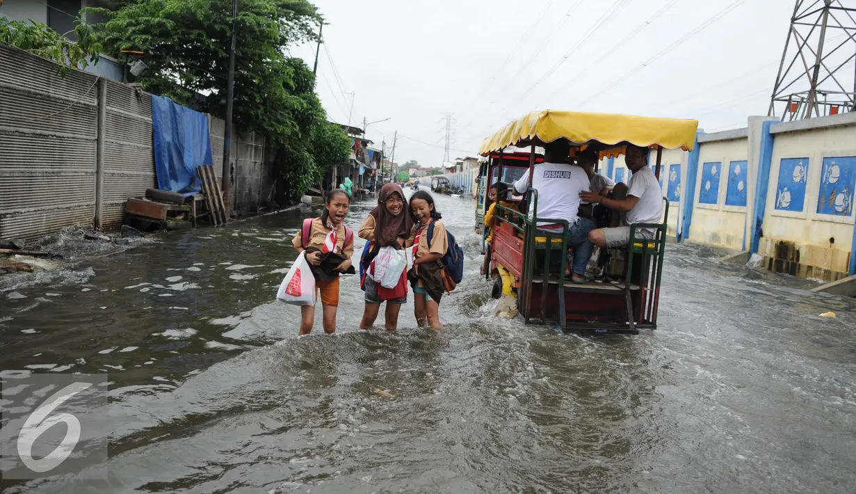 Sejumlah pelajar berjalan menembus banjir di Kawasan Muara Angke, Jakarta, Rabu (11/1). Akibat banjir ini juga aktivitas warga menjadi terganggu. (Liputan6.com/Gempur M. Surya)