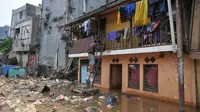 Warga terlihat turun menggunakan tangga dari lantai atas rumahnya menyusul surutnya air yang sempat merendam pemukiman mereka di kawasan Kampung Pulo, Jakarta, Selasa, (17/11). (Liputan6.com/Gempur M Surya)