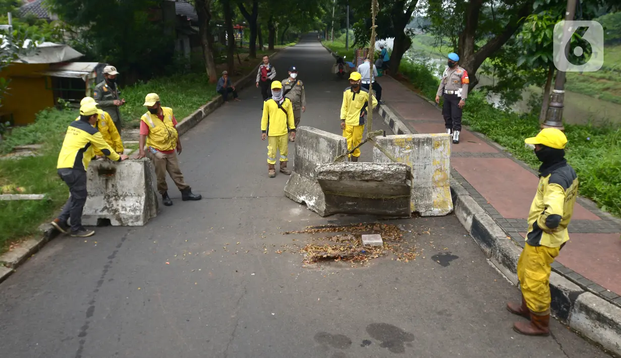 Petugas gabungan memindahkan beton pembatas dengan alat berat di Jalur Inspeksi Kanal Banjir Timur (KBT), Cipinang, Jakarta Timur, Kamis (30/12/2021). Kawasan KBT ditutup guna mencegah kerumunan warga yang hendak merayakan malam pergantian tahun. (merdeka.com/Imam Buhori)