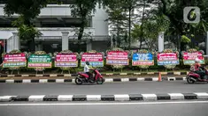 Pengendara melintasi karangan bunga di depan Gedung Kejaksaan Agung RI, Jakarta, Selasa (27/10/2020). Karangan bunga berasal dari korban terdampak kasus asuransi Jiwasraya yang mengharapkan kasus mega skandal itu bisa segera tuntas dan memberikan keadilan bagi mereka. (Liputan6.com/Faizal Fanani)
