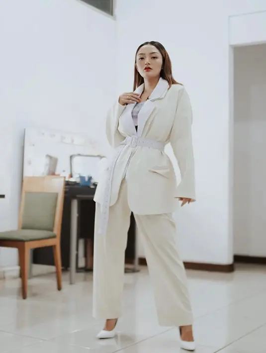 Siti Badriah tampil mengenakan one set putih gading yang terdiri dari blazer oversize dan loose pants. Belt putih dan high heels menunjang penampilannya. @sitibadriahh