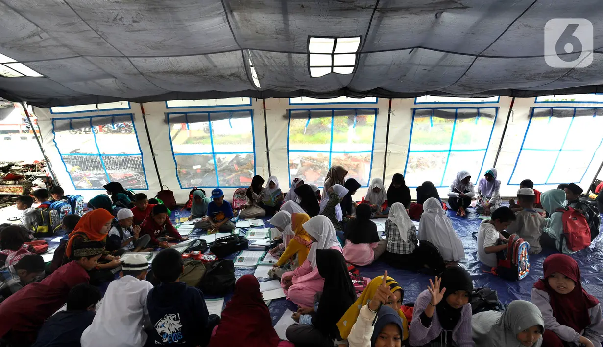Murid-murid korban gempa belajar pada tenda darurat yang dibangun di halaman sekolah di SDN Gintung, Mangunkerta, Cianjur, Jumat (23/12/2022). Lebih dari sebulan sejak musibah gempa bumi 5,2 SR sejumlah murid sekolah di Cianjur masih belajar pada tenda darurat. (merdeka.com/Arie Basuki)