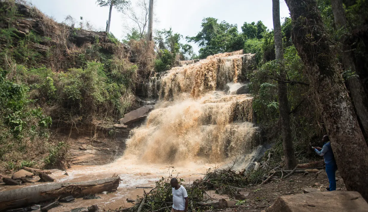 Warga berada di dekat air terjun Kintampo, Ghana (21/3). 20 siswa tewas setelah pohon tumbang dan menimpa mereka yang tengah berada di kolam air terjun pada Minggu (19/3) waktu setempat. (AFP Photo / Cristina Aldehuela)