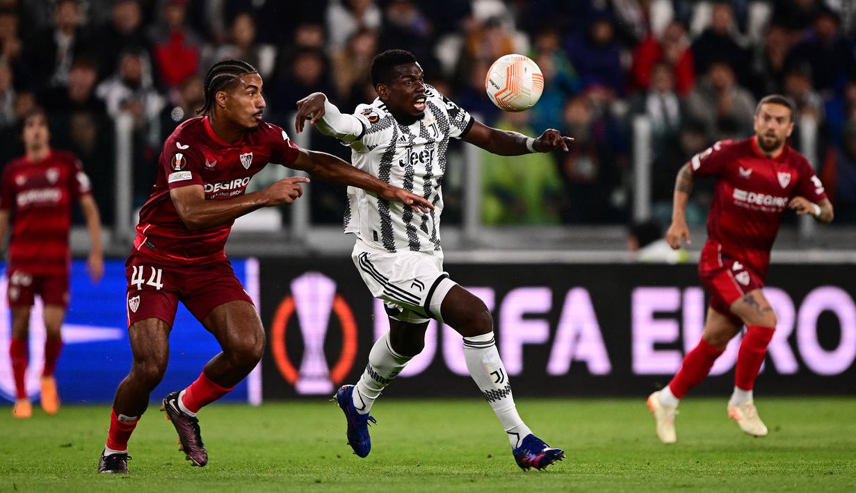 Pemain Juventus, Paul Pogba berusaha melewati penjagaan dari pemain Sevilla, Loic Bade pada laga leg pertama semifinal Liga Europa 2022/2023 di Allianz Stadium, Juventus, Jumat (12/05/2023) WIB. Laga berakhir dengan skor 1-1. (AFP/Marco Bertorello)