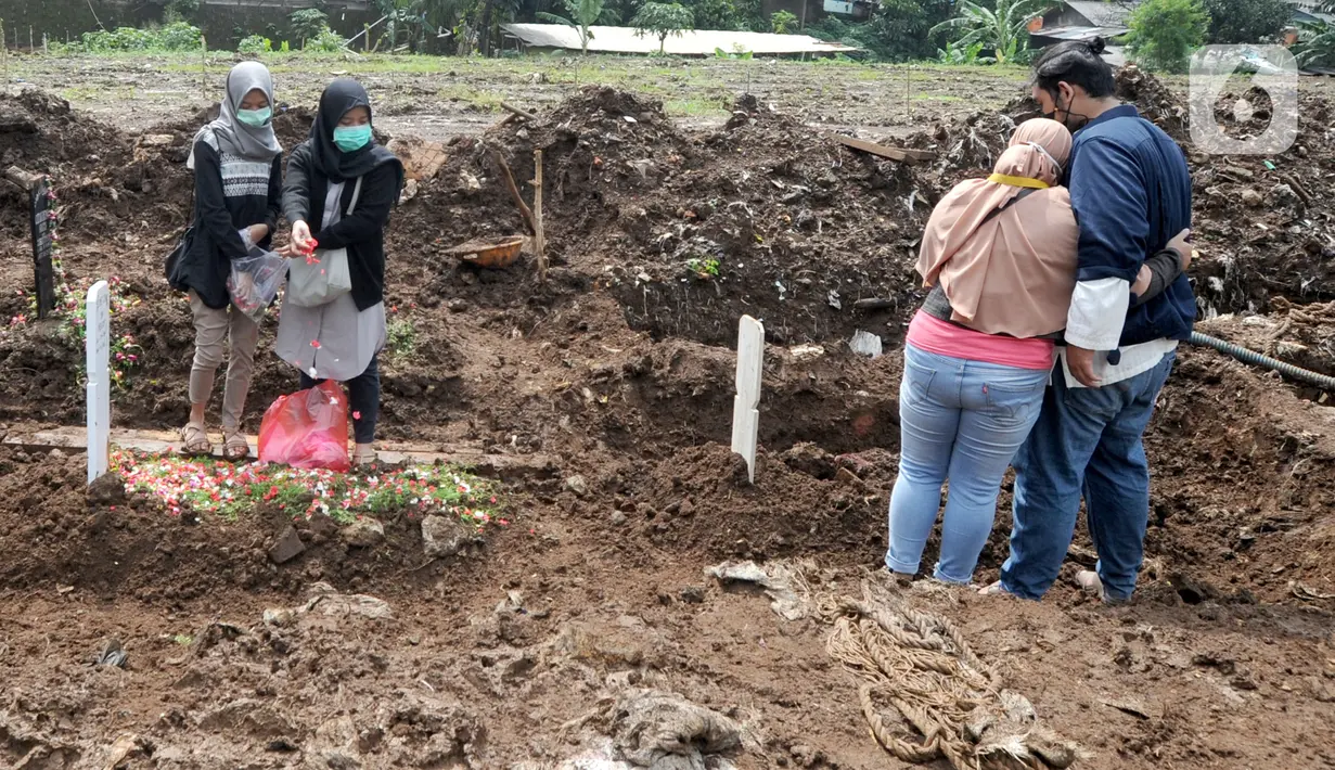 Kerabat dan keluarga jenazah kasus COVID-19 mengunjungi pemakaman di TPU Srengseng Sawah 2, Jakarta, Selasa (9/2/2021). TPU Srengseng Sawah 2 yang sudah lebih dari sepekan dibuka untuk pemakaman dengan protokol COVID-19 ini mampu menampung seribu lebih liang lahat. (merdeka.com/Arie Basuki)
