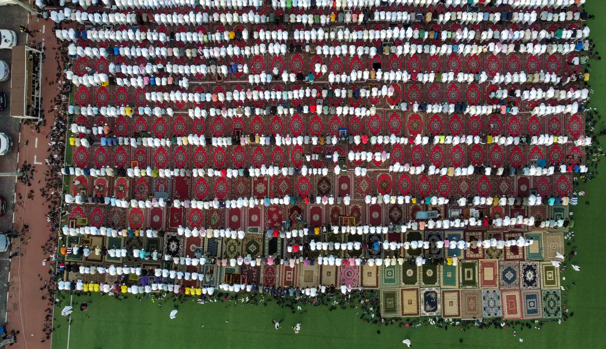 Dalam pandangan udara ini, umat Islam melaksanakan Sholat Idul Fitri , yang menandai berakhirnya bulan suci Ramadhan, di sebuah stadion sepak bola di Kota Kuwait, Jumat (21/4/2023). (Photo by YASSER AL-ZAYYAT / AFP)