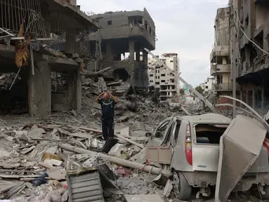 Seorang pria Palestina berjalan melewati puing-puing di tengah kehancuran akibat serangan udara Israel di lingkungan al-Rimal, Kota Gaza, pada 10 Oktober 2023. (MOHAMMED ABED/AFP)