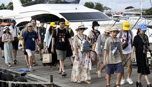 Turis China berjalan untuk menaiki kapal cepat untuk perjalanan dari Pulau Serangan ke Pulau Lombok di Denpasar, Bali, Rabu (25/1/2023). Sebelum pandemi Covid-19 pada 2020 lalu, turis China yang datang ke Serangan jumlahnya lumayan banyak. Dari puluhan sampai seratusan per hari. (AFP/Sonny Tumbelaka)