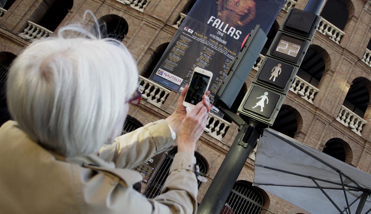 Seorang wanita mengabadikan lampu lalu lintas pejalan kaki yang bergambar sosok perempuan saat Peringatan Hari Perempuan Internasional di Valencia, Spanyol, Selasa (8/3/2016). (REUTERS/Heino Kalis)