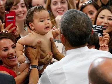 Presiden AS Barack Obama memegang bayi selama kunjungannya di Stasiun Udara Korps Marinir Iwakuni, Jepang (27/5). Kedatangan Obama ke Jepang untuk mennghadiri pertemuan G7. (REUTERS/Carlos Barria)