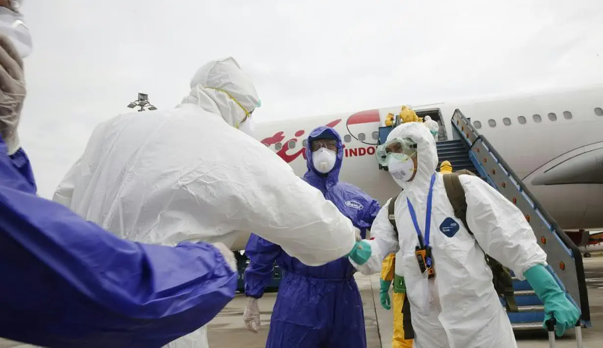 Petugas mengenakan alat pelindung saat mengevakuasi WNI dari Wuhan, China di bandara internasional Hang Nadim, Batam, Minggu (2/2/2020). Korban meninggal dunia akibat Virus Corona di seluruh wilayah daratan China  telah mencapai 304 orang. (Photo by Handout/Indonesian Embassy/AFP)