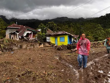 Warga berjalan melewati rumah-rumah yang rusak di sebuah desa yang terdampak banjir di Malalak, Sumatera Barat, Jumat 28 November 2025. Jelang akhir November 2025, bencana banjir bandang dan tanah longsor melanda sebagian besar wilayah pulau Sumatera. (AP Photo/Ade Yuandha)