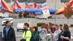 Orang-orang membawa tanda-tanda pemogokan Boeing saat mereka berjalan melewati pesawat Boeing 737 yang diparkir di dekat Boeing Field setelah aksi mogok kerja untuk Asosiasi Mekanik dan Pekerja Kedirgantaraan Internasional (IAM) di Seattle Union Hall di Seattle, Washington, pada tanggal 15 Oktober 2024. (Jason Redmond/AFP)