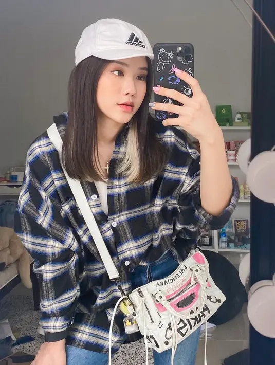 Padu padan kemeja over size kotak-kotak hitam dengan topi putih serta tas senada, gaya YouTuber kelahiran 1999 ini bisa jadi inspirasi remaja masa kini. (Liputan6.com/IG/@jessicajane99)