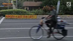 Pedagang siomay melintasi coretan "May Day Is Not Fun Day" di pembatas jalur bus Transjakarta kawasan Sarinah, Jakarta, Selasa (1/5). Aksi May Day di Jakarta meninggalkan jejak vandalisme yang dibuat kaum pekerja itu. (Merdeka.com/ Iqbal S. Nugroho)